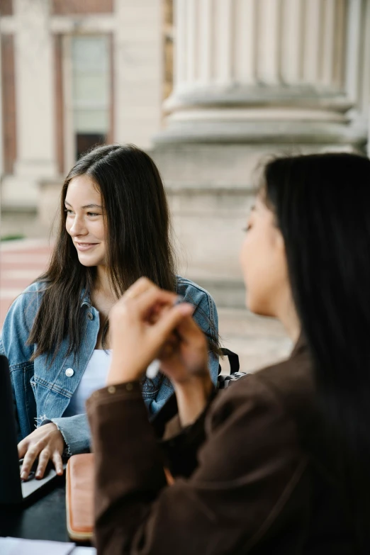 two women talking in front of a building