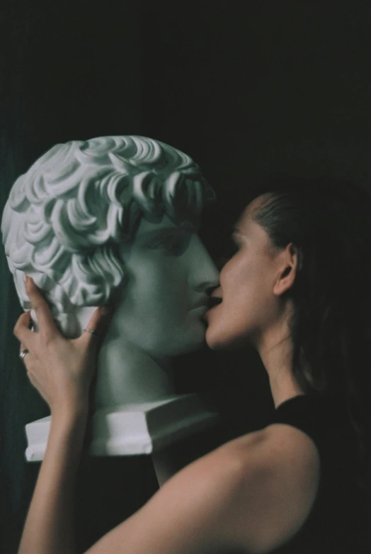 a girl with her face against a sculpture