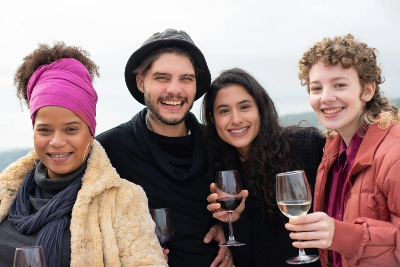 a group of four people smiling and holding wine glasses