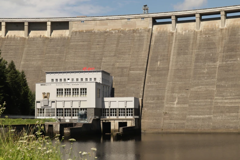 a dam on the edge of a river with a building and two pillars