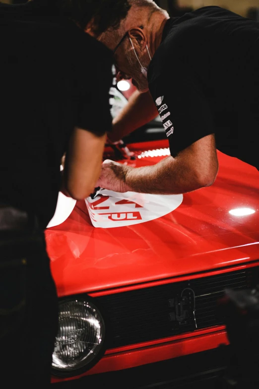 two men at a car show working on a car