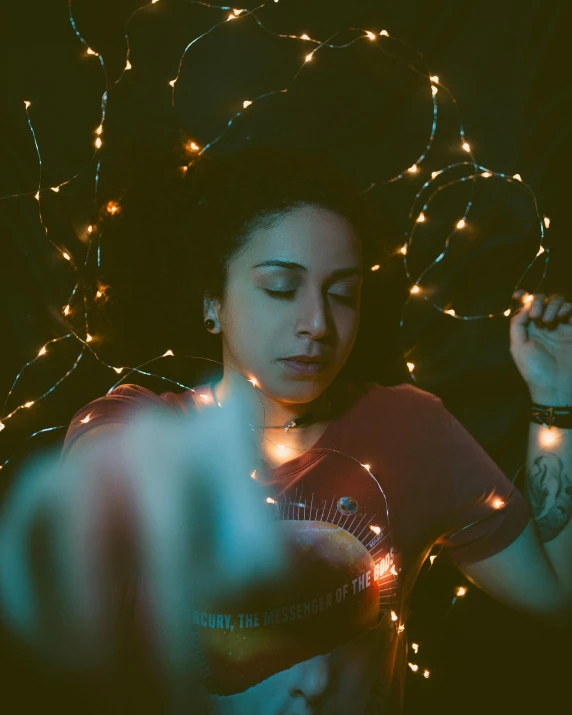 a person holding a cell phone under string lights