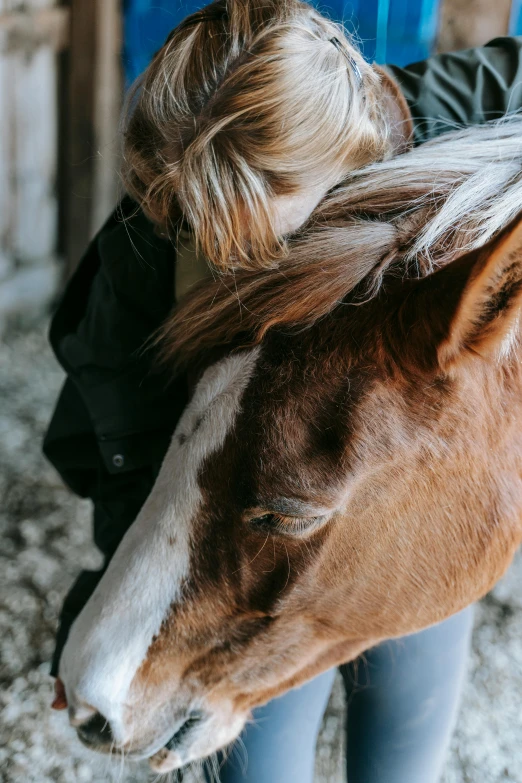 a woman wearing a black coat and white jacket next to a horse