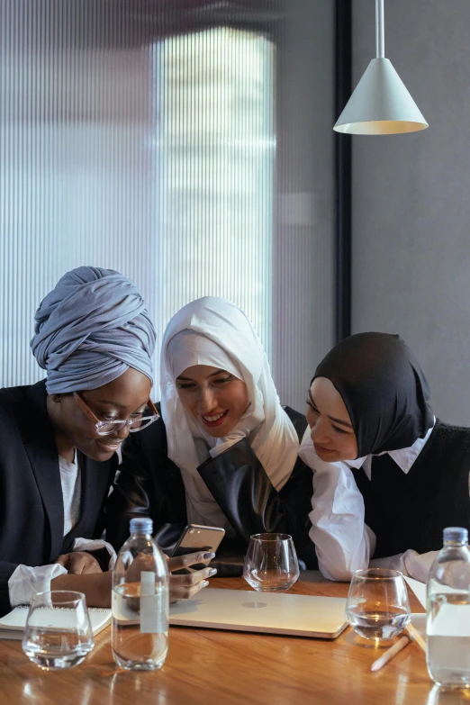 the women sit at the table using their phones