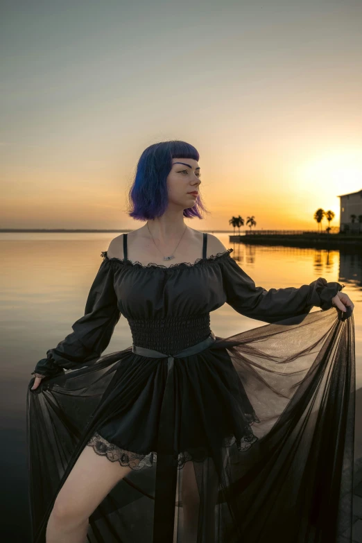 a woman in a sheer dress standing next to water