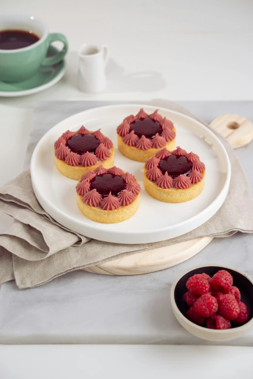 small pastries and raspberries sitting on a plate