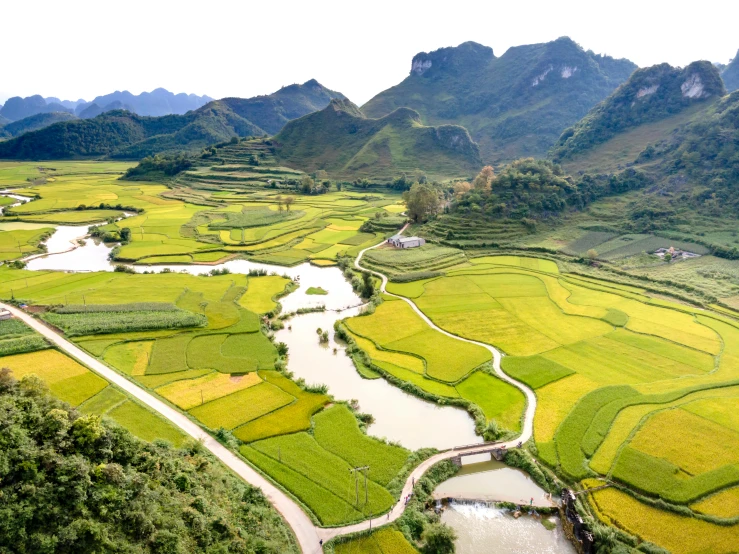 an aerial view of a river, farm land and mountains