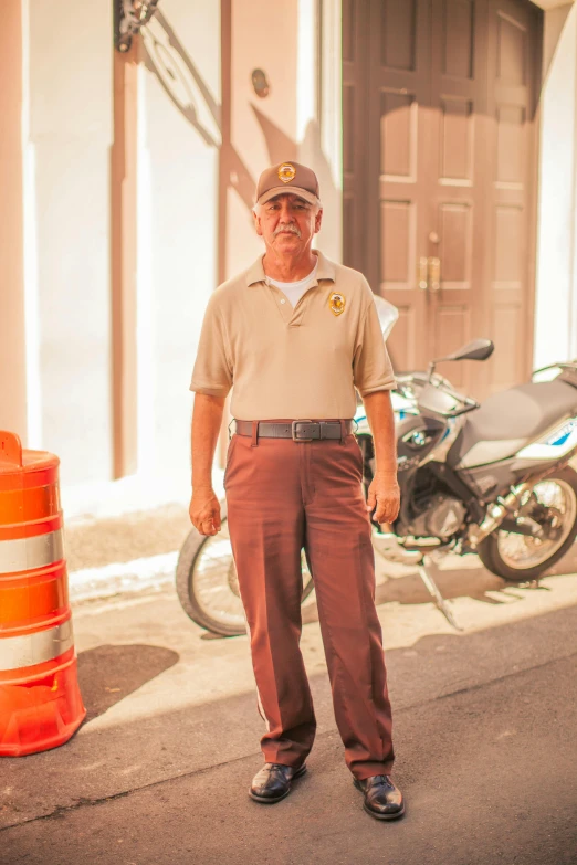 a man wearing a hat standing on a road near a motorcycle