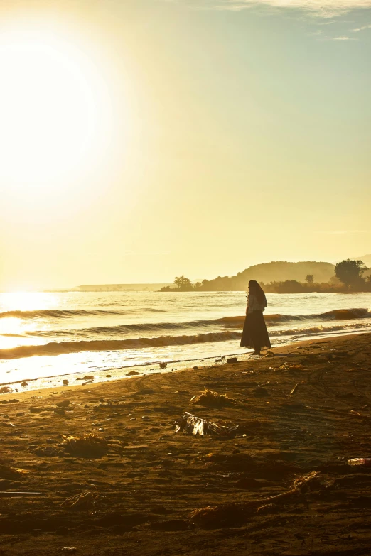 two people sitting and walking on a beach in the sunset