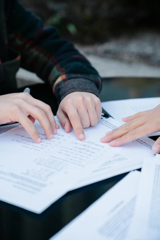 two hands holding over sheets of paper on a table