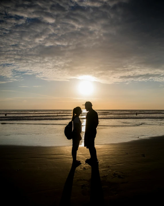 a couple standing on top of a beach near the ocean