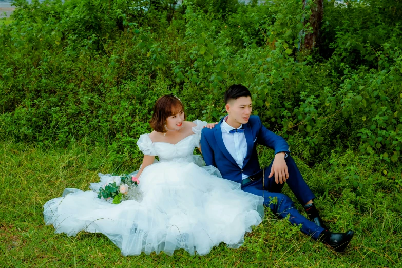 a young bride and groom sitting together on the ground