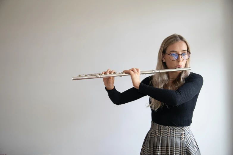 a woman wearing glasses, holding a flute in one hand