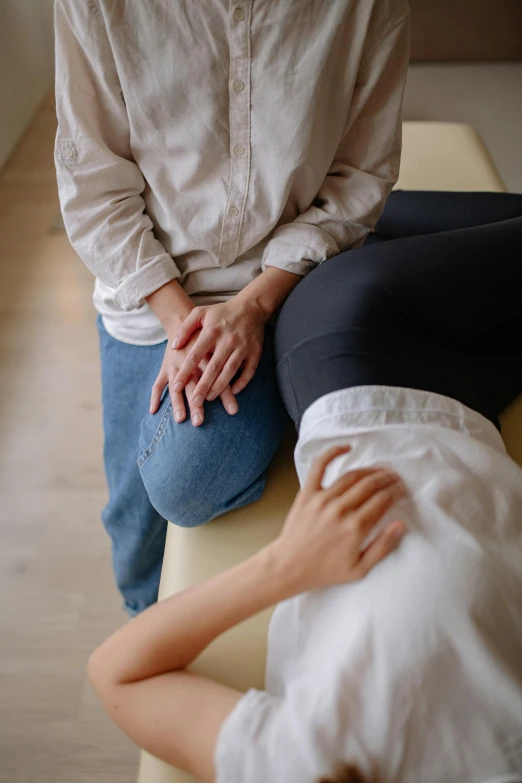 woman sitting on her stomach holding another person's hand