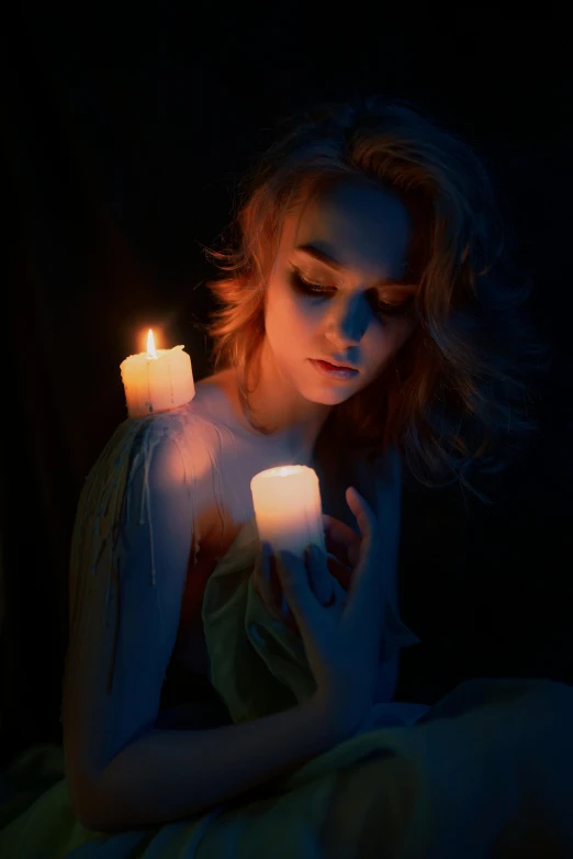 a beautiful young lady holding a lit candle