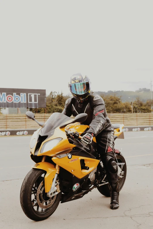 a man sitting on the seat of a yellow motorcycle