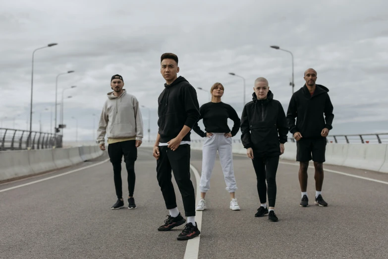 four young men wearing all black posing together on a bridge