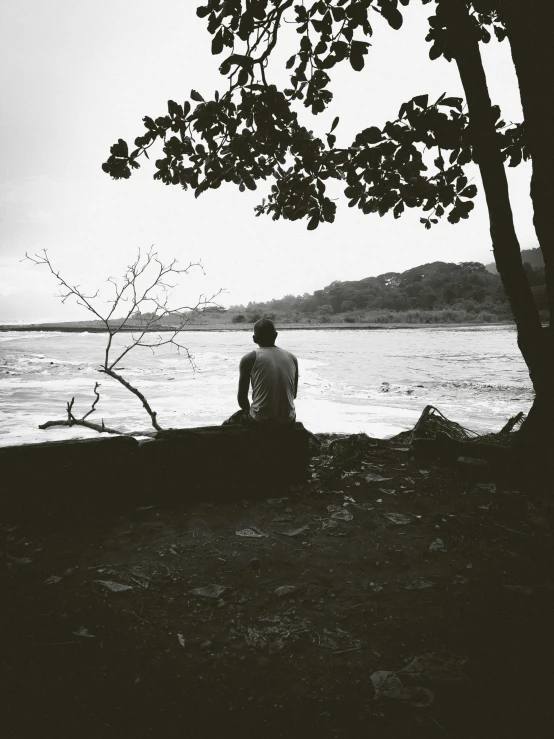 a person sitting at the edge of the water looking out to sea