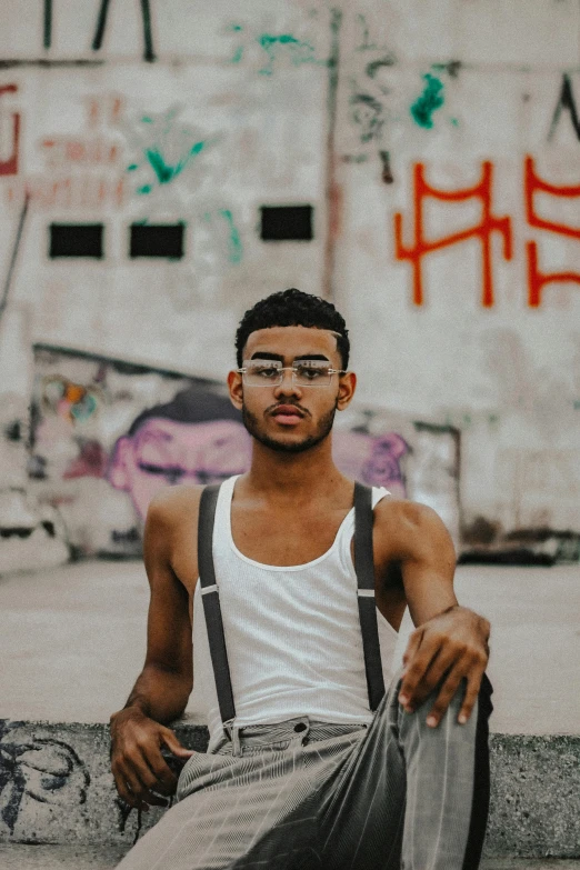 a man wearing glasses sitting on the side of a building