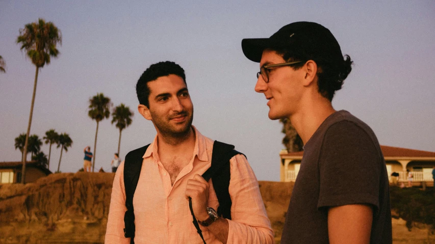 two men are talking in the sun on a hill