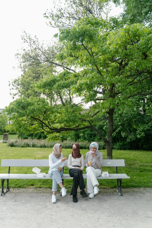 three people are sitting on a bench and one is typing