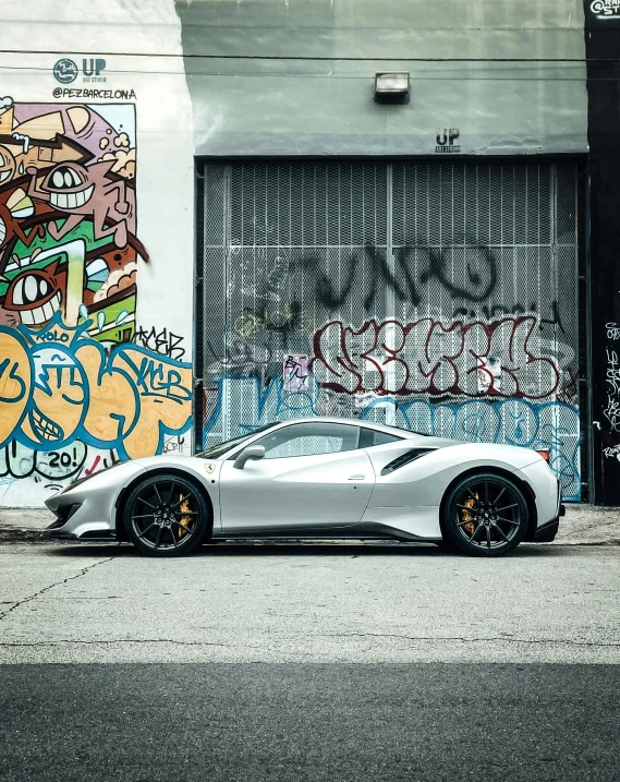 a silver car parked outside of a graffiti covered wall