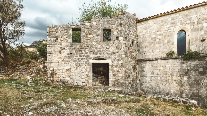 an old brick house sitting next to a dirt field