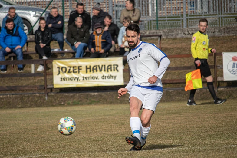 a man playing soccer during the day while people look on