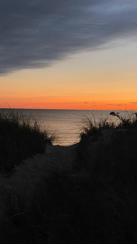 the dark silhouettes of two people on horseback, and the ocean in the background