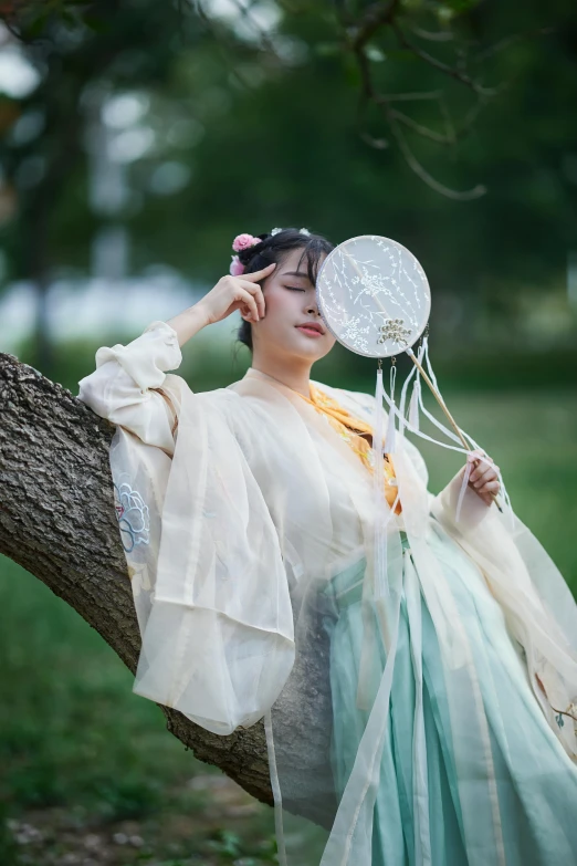 the girl with a fan is sitting on a tree