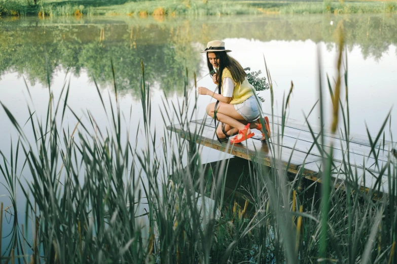 a woman sitting on top of a wooden pier next to a lake