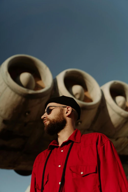 a man wearing sunglasses standing next to large potted flowers