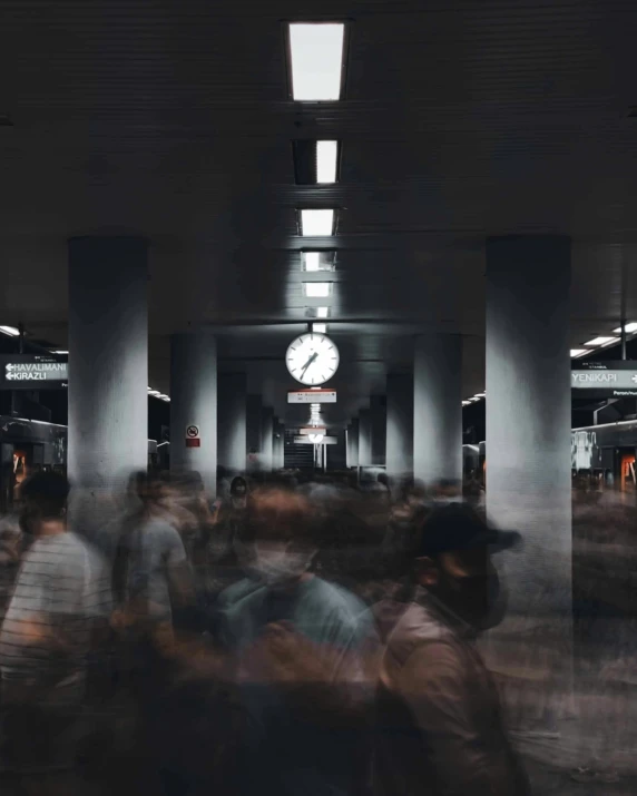 people walking around an airport lobby by a large clock