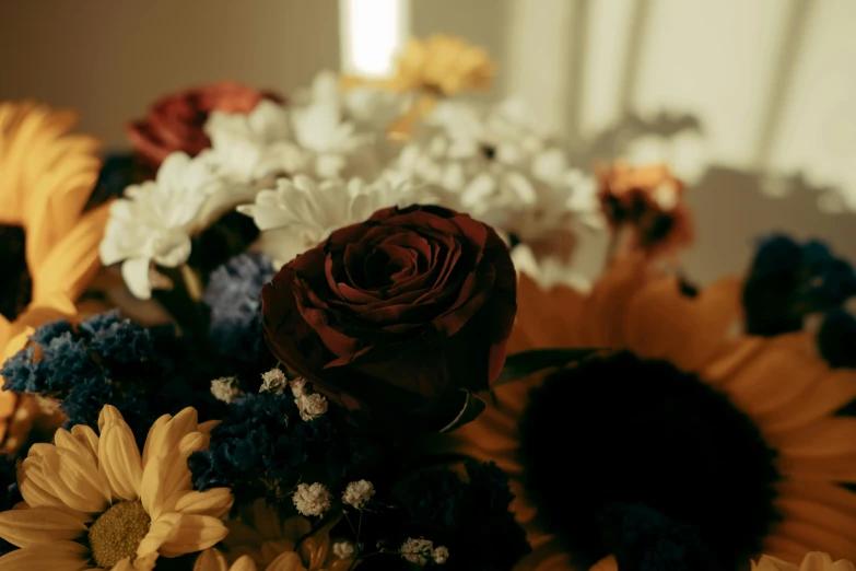 the red rose is sitting in the middle of the bouquet of sunflowers