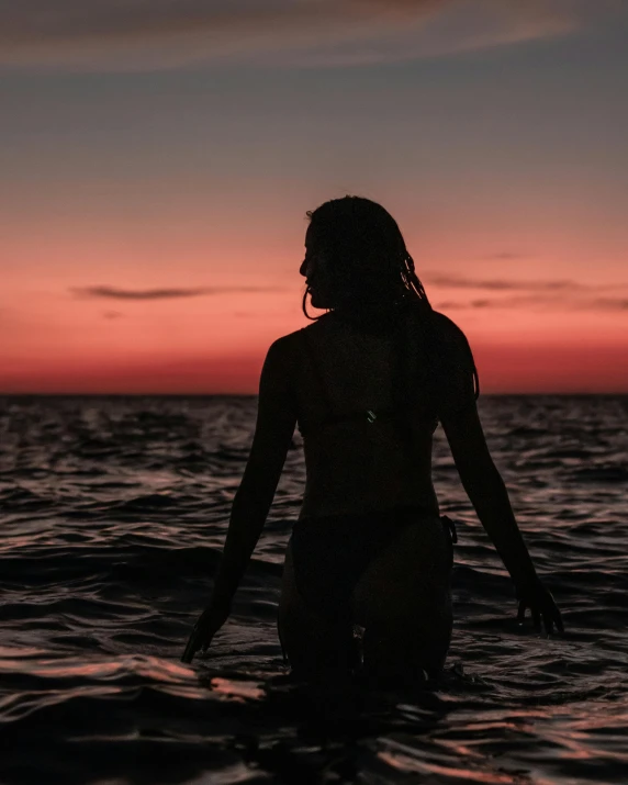 a person standing in the ocean at dusk