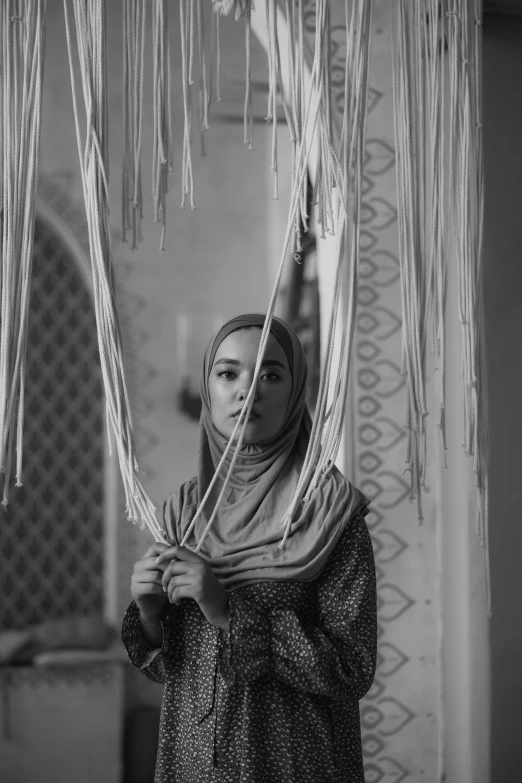 a woman is standing in a room holding a scarf over her head