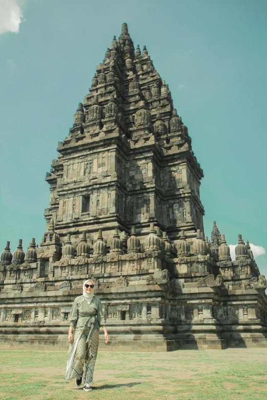 a woman in an ornate style dress walking past a very tall tower