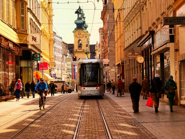 a trolley rides along the street near many people