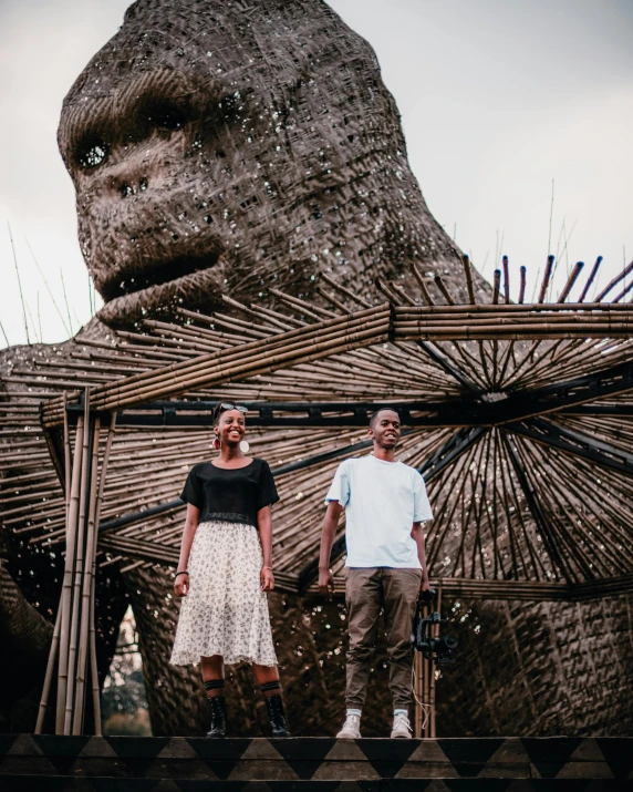 an african couple pose in front of the huge statue