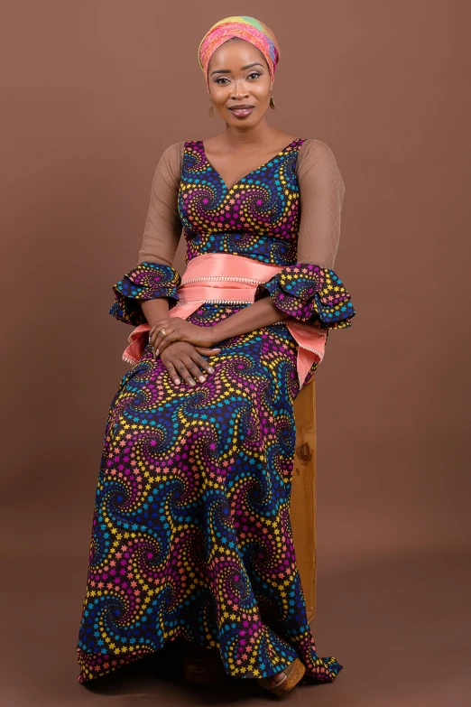 a woman in african style clothes is sitting on a chair