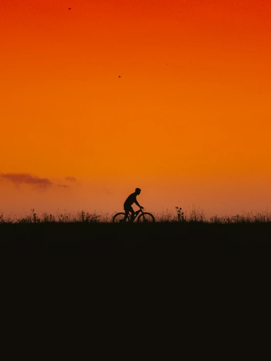 an image of silhouette of man riding a bike at sunset