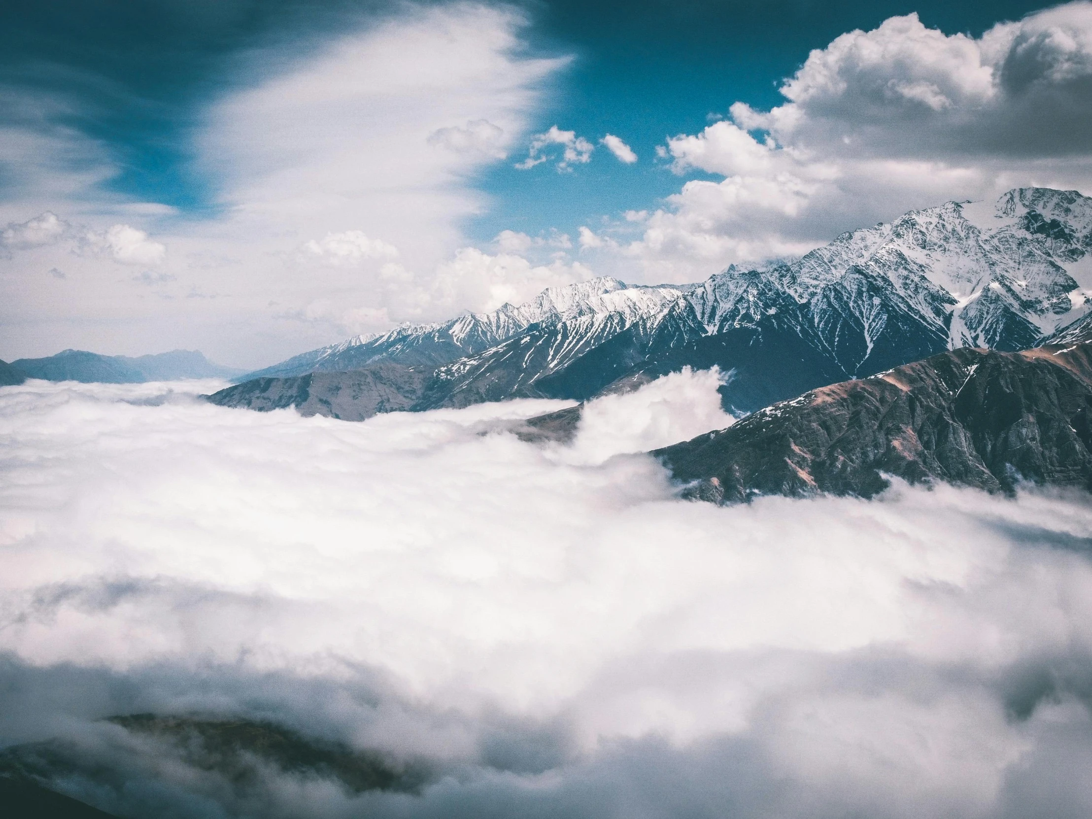 a snowy mountain range and the sky with clouds below