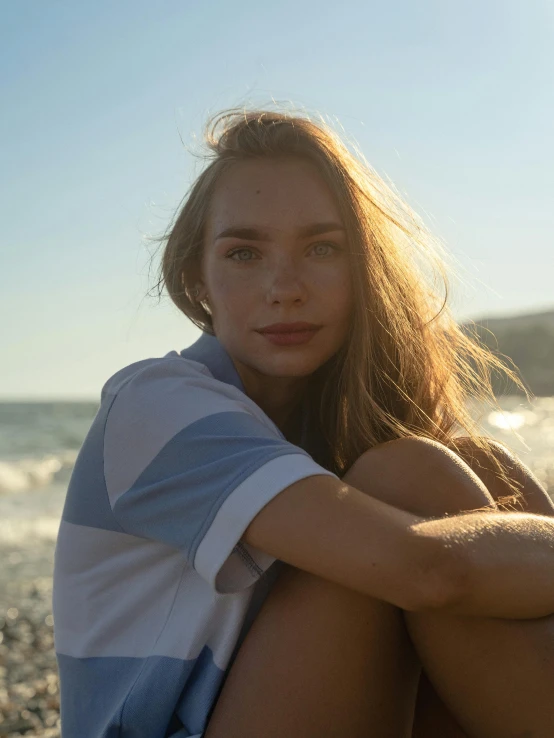 a young woman is sitting on a rock near the ocean