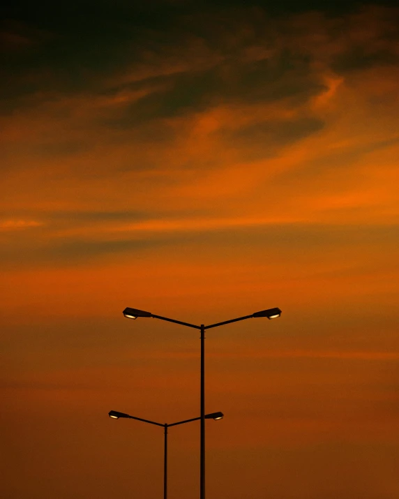 an orange sky over the top of a light pole