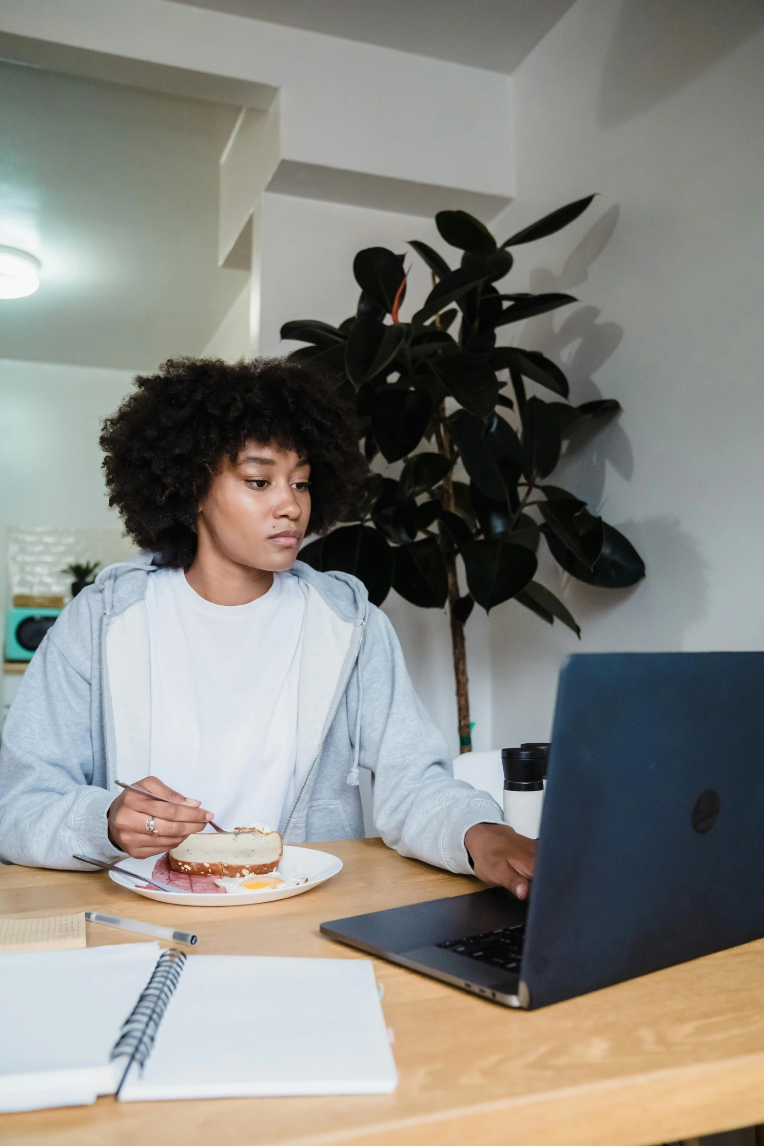 woman eating lunch while working on laptop