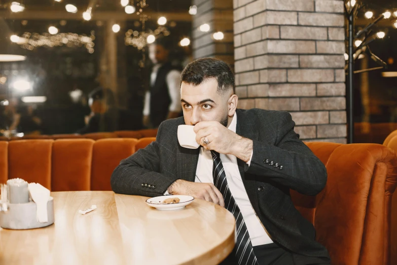 a man is drinking coffee and holding a napkin