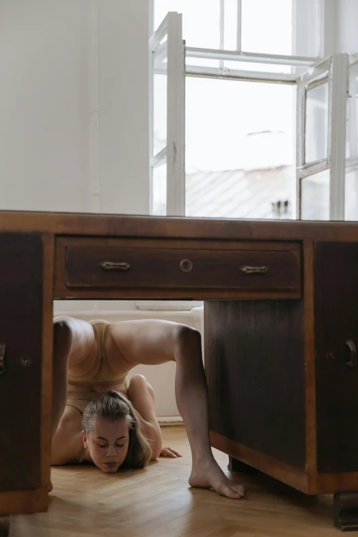 a woman wearing beige underwear lying on the ground under a table