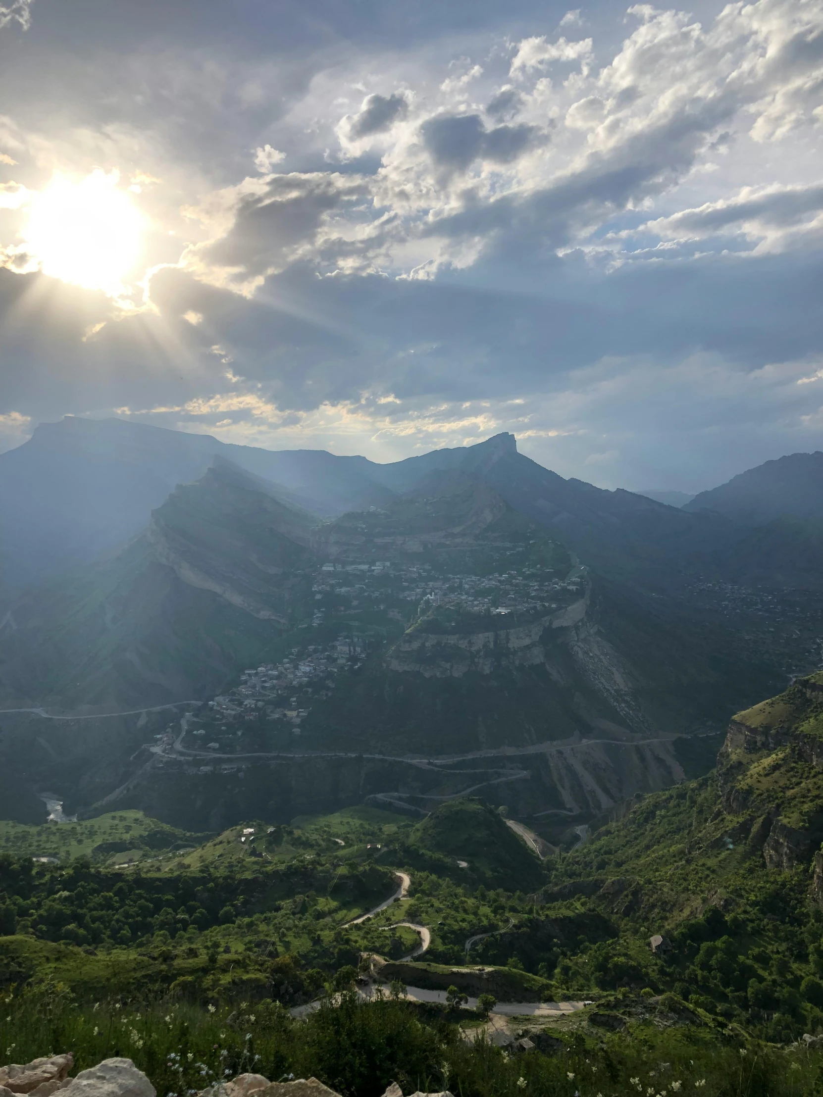 the sun shines bright over a valley in a mountainous region