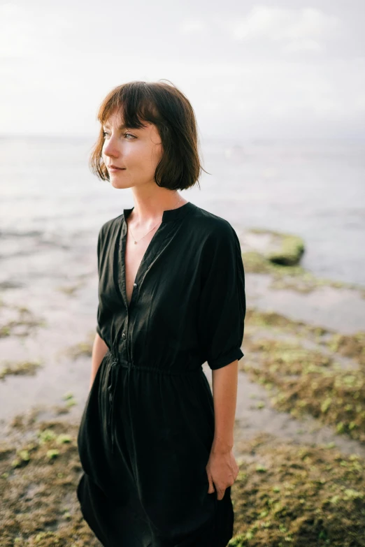 the woman is standing on the beach by the water