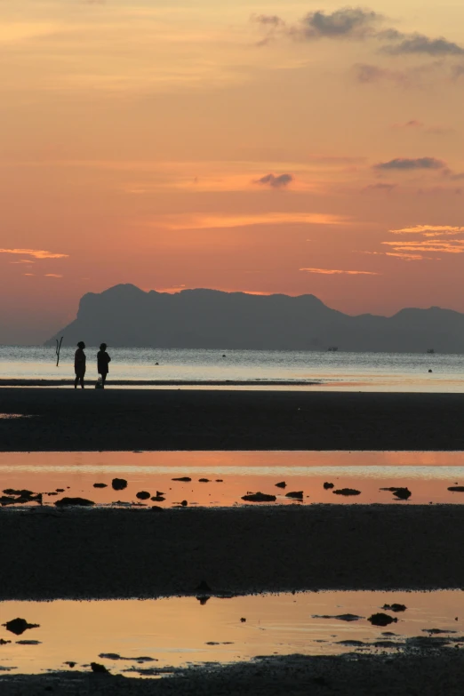 a couple walks along the shore with an ocean in front